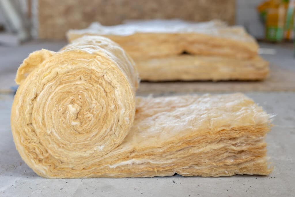 Rouleau de laine de roche posé sur le sol du grenier d’une maison en construction pour une isolation thermique et acoustique efficace