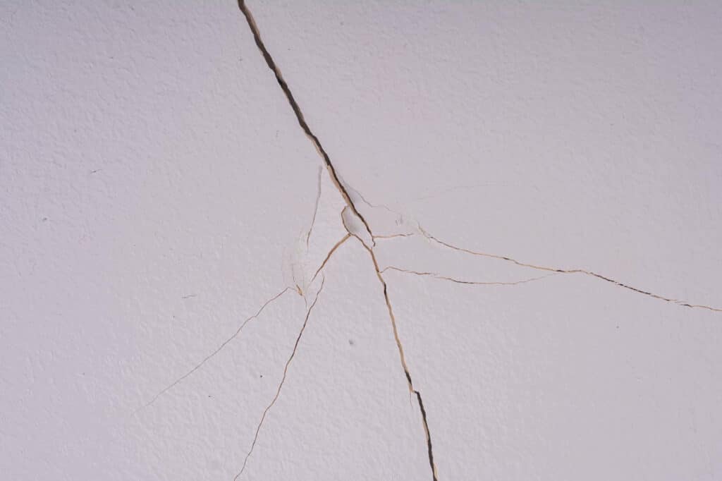 Fissure structurelle large de type crevasse sur un mur.