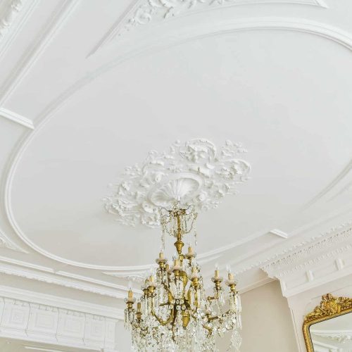 plafond orné de moulures décoratives avec un lustre suspendu au centre apportant élégance et raffinement
