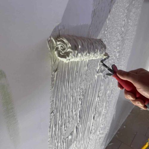 rouleau chargé d’enduit prêt à être appliqué sur une surface murale ou un plafond
